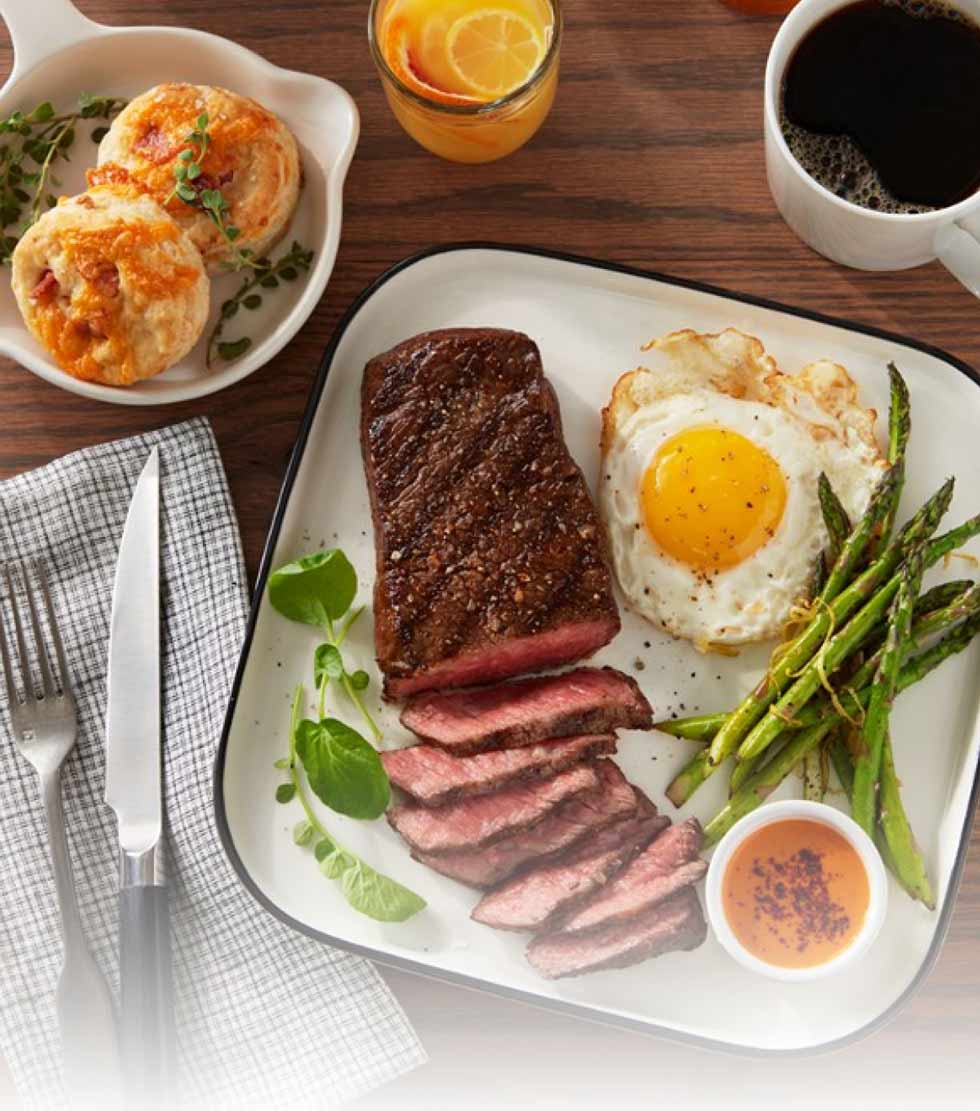 Grilled Denver steak with sunny side up egg, asparagus tips, bacon cheddar biscuits and peri peri dipping sauce