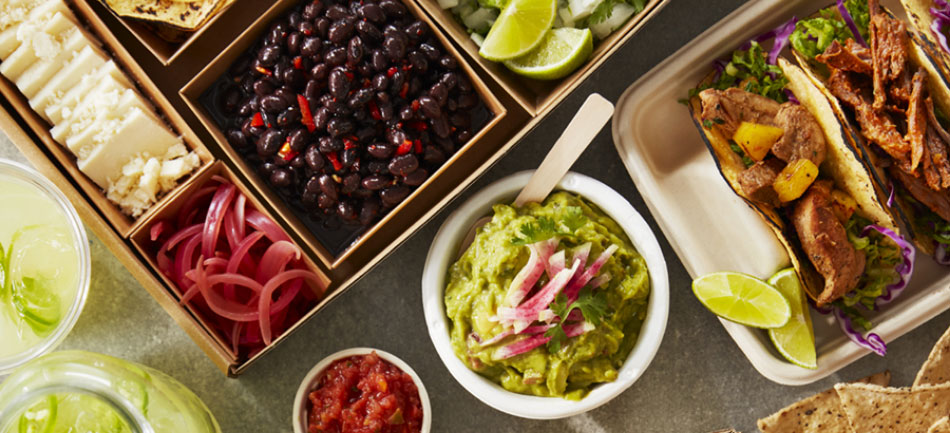 Fresh food such as guacamole, limes and black beans served in individual dishes