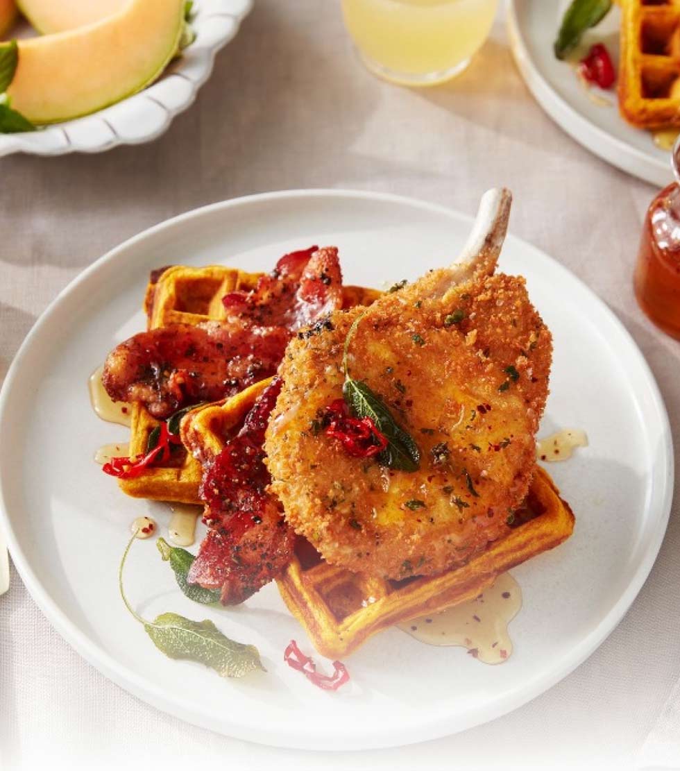 Breaded pork chop with sweet potato waffles, candied bacon and a hot honey drizzle